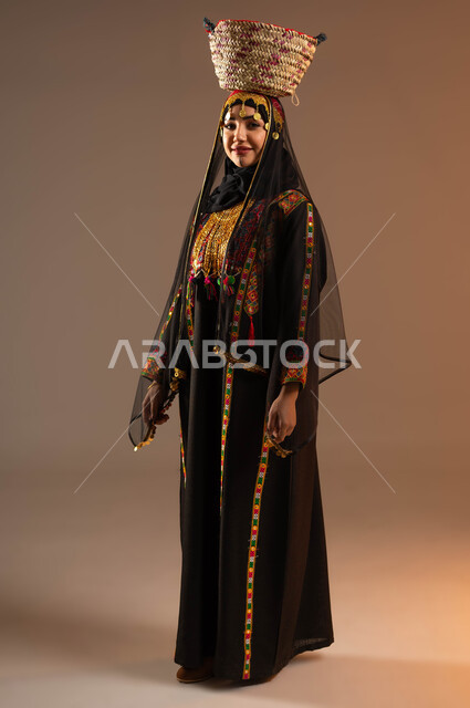 ارتداء زي المنطقة الوسطى في المناسبات الوطنية, مهن وحرف يدوية شعبية, بورتريه لإمرأة عربية خليجية سعودية ترتدي الشيلة والهامة والبشت تضع على رأسها سلة مصنوعة من القش, يوم بدينا 1727م, ذكرى تأسيس الدولة السعودية الأولى في 22 فبراير, صورة الجسم بالكامل, خلفية بيج