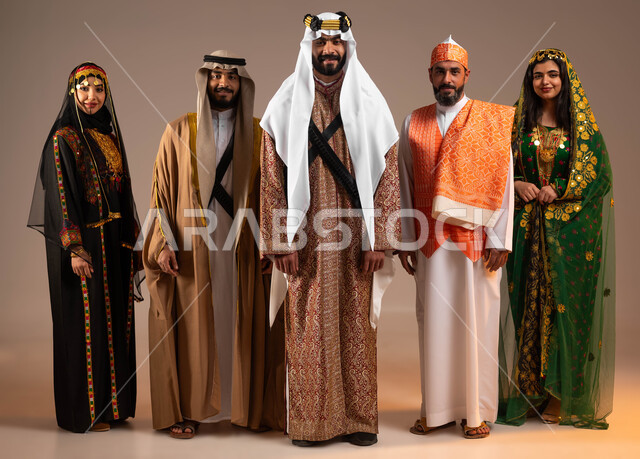 الوقوف بفخر واعتزاز بإنجازات الوطن, بورتريه لمجموعة رجال ونساء عرب خليجين سعوديين يرتدون الأزياء التقليدية الشعبية في المناسبات الوطنية ينظرون إلى الكاميرا, يوم بدينا 1727م, ذكرى تأسيس الدولة السعودية الأولى في 22 فبراير, صورة الجسم بالطول الكامل, خلفية بيج