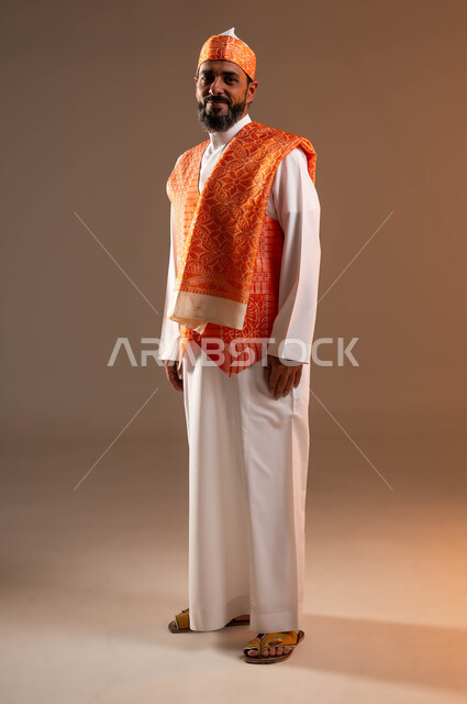 يوم بدينا 1727م, ذكرى تأسيس الدولة السعودية الأولى في 22 فبراير, الوقوف بثقة وفخر بإنجازات البلاد، ارتداء أزياء المنطقة الغربية في المناسبات الوطنية, بورتريه لرجل عربي خليجي سعودي يرتدي السديري والثوب التقليدي ينظر إلى الكاميرا, صورة الجسم بالكامل, خلفية بيج