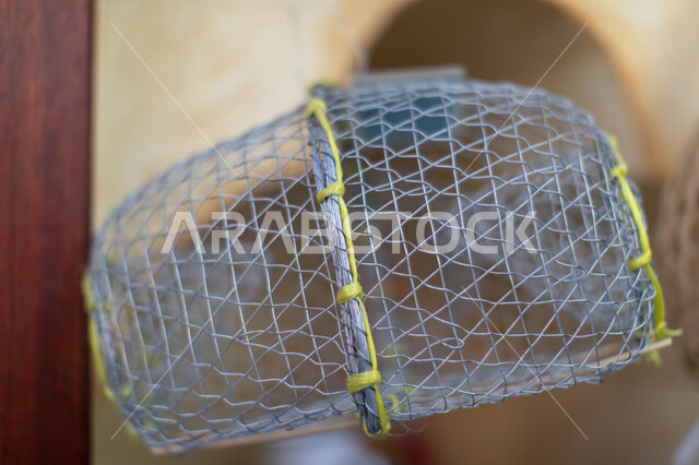 Professions and handicrafts in the popular Muharraq market in the Kingdom of Bahrain, famous traditional commercial landmarks and markets, a metal net for fishing and marine creatures.