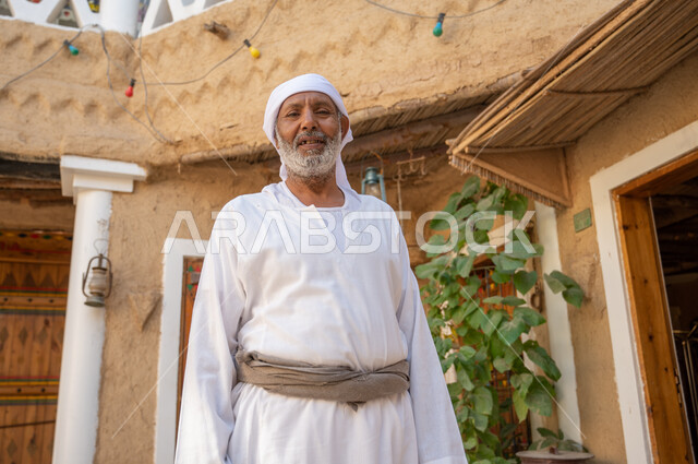 يوم بدينا 1727م، الفخر والتباهي بالتراث الوطني، البيوت الطينية الاثرية القديمة، رجل عربي خليجي سعودي كبير بالسن يرتدي الزي الشعبي ينظر إلى الكاميرا، ذكرى تأسيس الدولة السعودية الاولى 22 فبراير