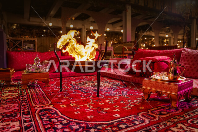 صورة مقربة لمجلس عربي شعبي فاخر، العادات والتقاليد السعودية في تقديم القهوة العربية بالدله والفنجان، التدفئة على موقد الحطب في الأجواء الشتوية، جلسات شعبية تلقيدية