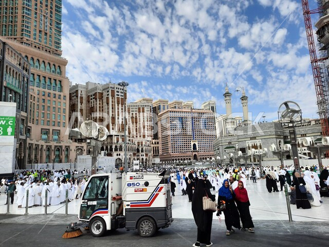 Performing Hajj and Umrah rituals, cleaning the outer courtyard of the Holy Mosque in Mecca, sacred Islamic places and landmarks, the arrival of pilgrims and Umrah performers from all over the world to worship and get closer to God, luxury hotels and towers surrounding the Grand Mosque, a view of the blue sky filled with clouds