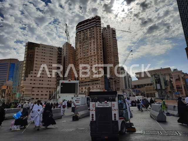 أداء مناسك الحج والعمرة، تنظيف الساحة الخارجية للحرم المكي الشريف في مكة المكرمه، أماكن ومعالم اسلامية مقدسة, قدوم الحجاج والمعتمرين من كل انحاء العالم للعبادة والتقرب الى الله, الفنادق والأبراج الفاخرة المحيطة بالمسجد الحرام, منظر السماء الزرقاء المليئة بالغيوم