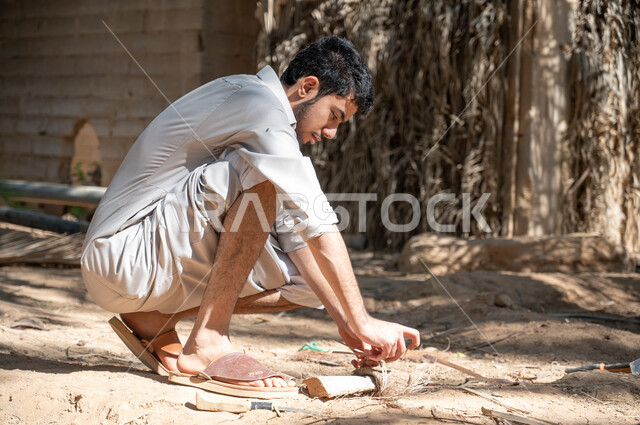 اتقان مهنة الفلاحة ،شاب عربي خليجي سعودي يرتدي الزي الشعبي يقوم بربط سعف النخل في أحد مزارع النخيل في المملكة، دور الفلاحين السعوديين في رعاية الاراضي الزراعية ،الحفاظ على تراث زراعي غني، الاهتمام في زراعه اشجار النخل، محاصيل زراعية محلية