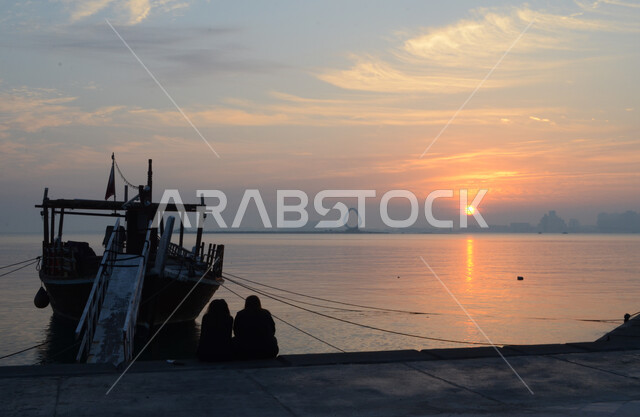 الاستمتاع مع الأصدقاء في العطلة الصيفية, وسائل النقل البحرية, مركب شراعي على كورنيش الدوحة وقت غروب الشمس،  قضاء وقت ممتع في الابحار, رحلات بحرية ترفيهيه, المناظر الطبيعيه على سواحل الخليج العربي في المملكة العربيه السعودية