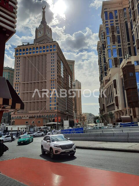 الفنادق والأبراج الفاخرة المجاورة لمبني برج الساعة الملكي، حركة السيارات في الطرقات والشوارع المعبدة في النهار في المملكة، الاهتمام بالبناء والتطوير العمراني في مكة المكرمة، أسلوب الحياة في السعودية