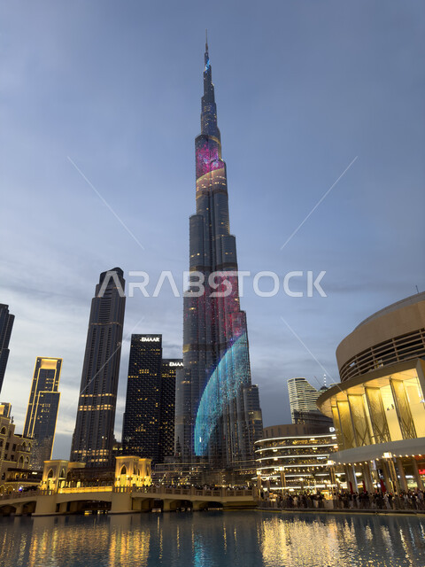 الأبراج وناطحات السحاب المحيطة ببرج خليفة المضاء في الليل، معالم سياحية مشهورة في الإمارات العربية المتحدة، الواجهه البحرية لإمارة دبي، الفن الهندسي المعماري المتطور والمتقدم للمنشآت التجارية والسكنية