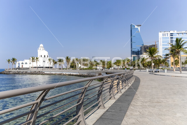 The architectural art of the Corniche Tower building in the city of Jeddah, Al Jazeera Mosque overlooking the waterfront in the Kingdom of Saudi Arabia, interest in planting trees and green plants in the coastal city, enjoying the water landscape during the day