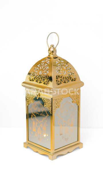 Lamps and lights in the spiritual Ramadan atmosphere, lighting and decorations for the holy month of Ramadan, traditional Islamic lanterns and antiques to celebrate the coming of the month of goodness, a metal Arabic lantern decorated in gold, a white background.
