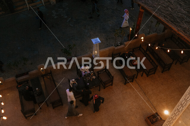 الاستمتاع و قضاء الوقت مع الاصدقاء، صورة من الأعلى لمجموعة من الشباب العرب يجلسون في أحد المقاهي في سوق القيصرية في مدينة الاحساء، زيارة الاماكن الشعبية السياحية القديمة