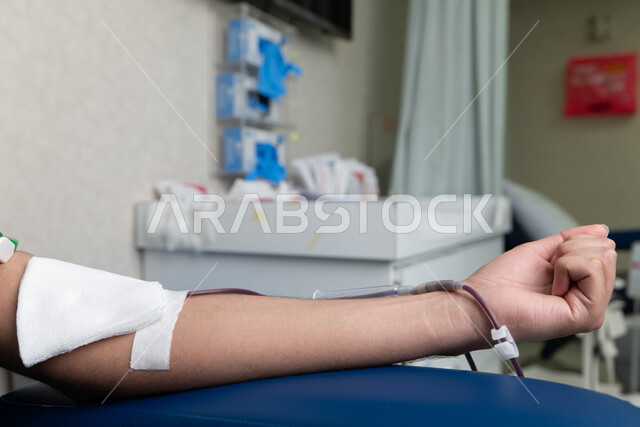 حملة التبرع بالدم داخل إحدى المشافي في المملكة العربية السعودية، تنشيط الدورة الدموية، مفهوم الطب والرعاية الصحية, إجراءات تطوعية لتلبية احتياجات طبية، صورة مقربة ليد رجل   يتبرع بدمه