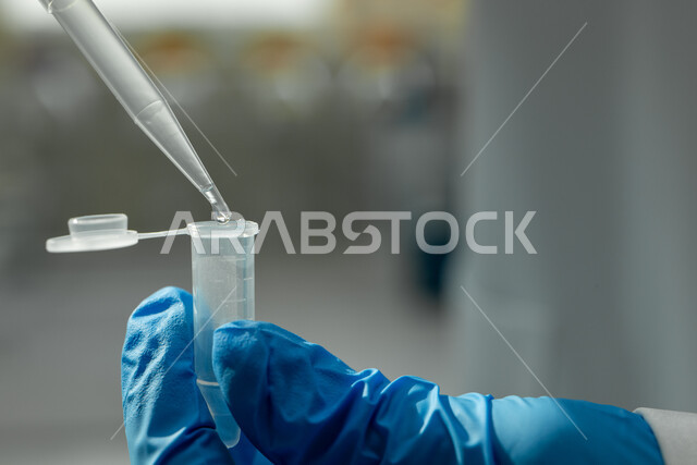 استخدام الأنبوبة الزجاجية المعقمة لتحليل العينات المختلفة، صورة مقربة ليد مخبري يرتدي القفازات يقطر السائل من الماصة إلى أنبوب الاختبار، إجراء تجارب وبحوث علمية عبر التكنولوجيا الحيوية، مختبرات الفحوصات الطبية والتحاليل الكيمائية، معمل الصناعات الدوائية