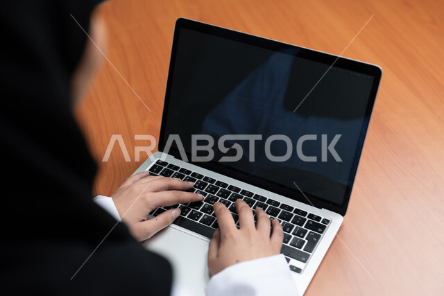 امتلاك مهارات عالية في قيادة الحاسب الآلي، صورة مقربة لأيدي إمرأة عربية خليجية سعودية تقوم بالعمل على الحاسب المحمول بشاشة سوداء فارغه، مهام ووظائف إدارية مكتبية نسائية، إدخال البيانات والكتابة من خلال لوحة المفاتيح، دمج العمل مع التقنية والتكنولوجيا 