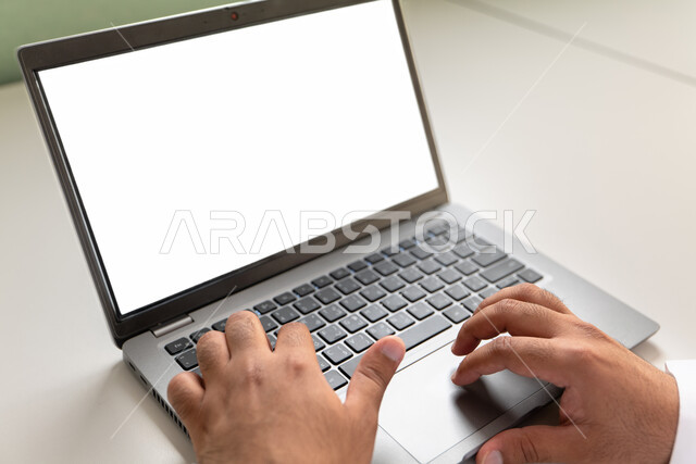 إدخال البيانات والكتابة من خلال لوحة المفاتيح، دمج العمل مع التقنية والتكنولوجيا، امتلاك مهارة الكتابة السريعة على الكيبورد، صورة مقربة لأيدي رجل عربي خليجي سعودي يقوم بالعمل على الحاسب المحمول،  مهام وظائف إدارية مكتبية