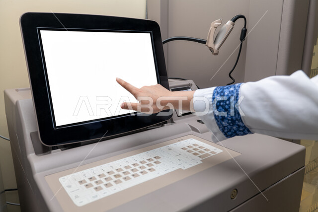 A close-up photo of a doctor’s hand pointing to something on a computer screen, the development and progress of the medical sector with new technology, a medical device in a modern hospital, health centers and laboratories in Saudi Arabia.