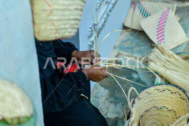 التراث والأصالة في المملكة العربية السعودية, حرف يدوية تاريخية, أعمال وصناعات قديمة, استخدام أوراق النخيل المجففة في صناعة السلل, منتجات محلية وطنية, مهن شعبية تقليدية, صورة من الجانب ليد إمرأة عربية خليجية سعودية تقوم بجدل سعائف الخوص