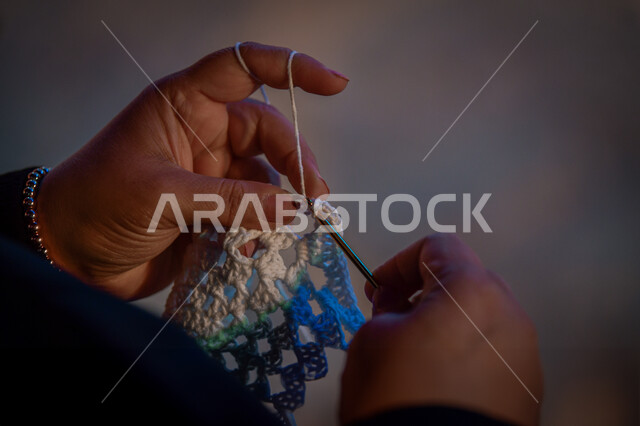  أعمال تقليدية شعبية, مشغولات وصناعات يدوية, فن ومهارة الخياطة والغزل, صورة مقربة ليد إمرأة عربية خليجية سعودية تقوم بحياكة الصوف, استخدام خيوط صوفية ملونة, الفخر والتباهي التراث الخليجي السعودي, مهن وحرف نسائية