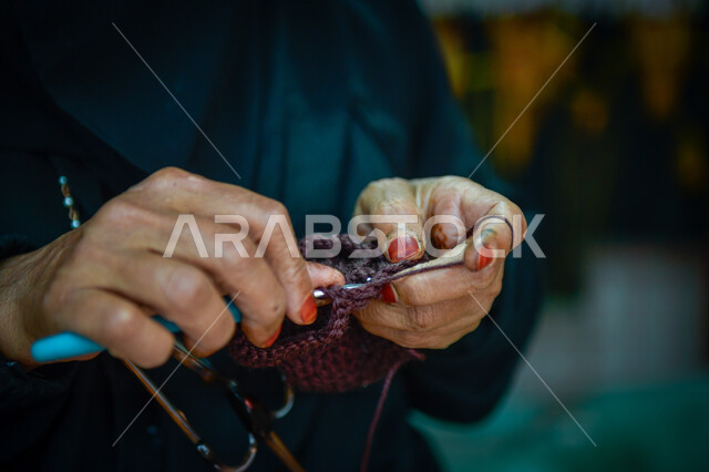 مهن وحرف نسائية قديمة, مشغولات وصناعات يدوية, أعمال تقليدية شعبية, فن ومهارة الخياطة والغزل, صورة مقربة ليد إمرأة عربية خليجية سعودية تقوم بحياكة الصوف, استخدام خيوط صوفية ملونة, الفخر والتباهي التراث الخليجي السعودي