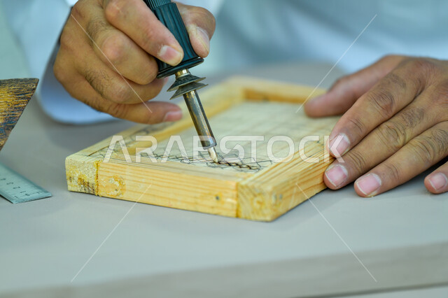 التخطيط و الرسم اليدوي، صورة مقربة لأيدي رجل عربي خليجي سعودي يقوم بالنقش على قطع خشبية ،مهن وحرف شعبيه تراثية، الأصالة والعراقة والفخر و الاعتزاز بالتراث السعودي، تحف أثرية تقليدية