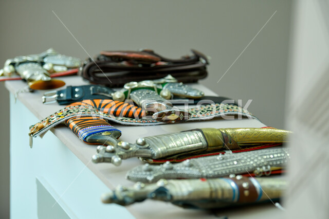 الخناجر الشعبية القديمة على طاولة بيضاء، صورة مقربة لمجموعه من التحف التراثية المعدنية ، احياء التراث السعودي، اكسسوارات وانتيكا اثرية