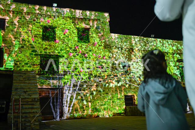 انعكاس صورة الأشجار والنباتات الخضراء على المباني التراثيه الشعبيه, أماكن سياحيه ترفيهيه عائليه في السعوديه، صورة مقربة من الخلف لفتاة عربية خليجية سعودية برفققة عائلتها في نزهه خارجيه، الاهتمام بالابناء والاعتناء بهم، الحفاظ على التراث السعودي