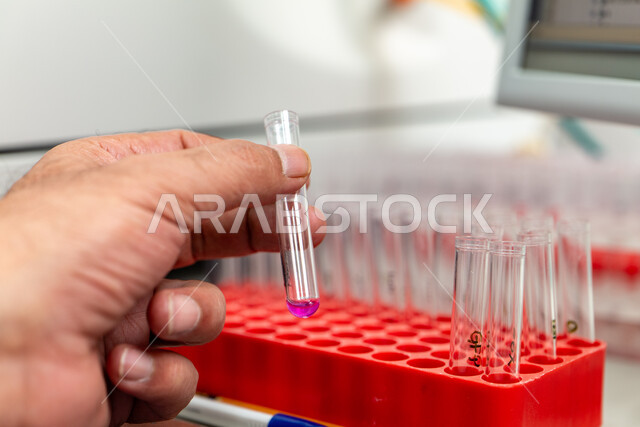 استخدام الأنابيب الزجاجية المعقمة لتحليل العينات المختلفة، إجراء تجارب وبحوث علمية عبر التكنولوجيا الحيوية، مختبرات الفحوصات الطبية والتحاليل الكيمائية، معمل الصناعات الدوائية، صورة مقربة ليد مخبري يمسك أنبوبة الاختبار