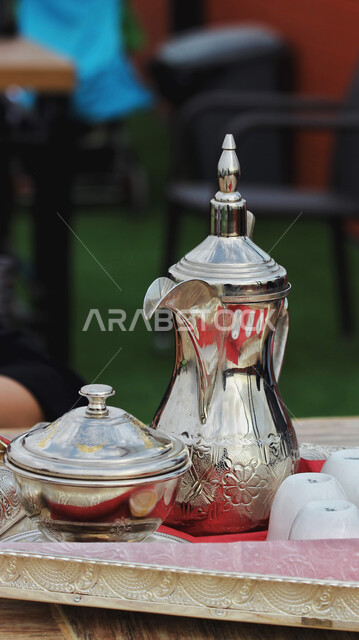 مفهوم الاكرام وحسن الاستقبال، منتجات و محاصيل وطنية محلية, تقديم القهوه الساخنه للضيوف، الضيافة في الأعياد والمناسبات الإسلامية، صورة مقربة لدلة قهوة عربية سعودية أصيلة نحاسية في احد الكافيهات