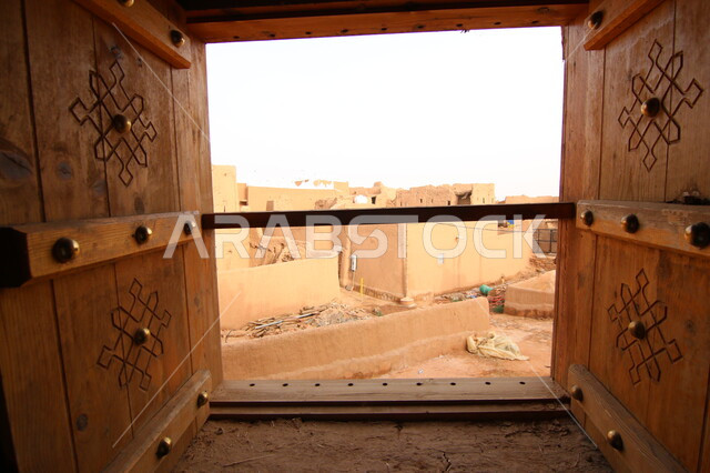 صورة من داخل احدى البيوت الطينية القديمة لنافذة خشبية مطلة على أحياء قرية أشيقر في مدينة الرياض، الآثار التاريخية العريقة في المملكة العربية السعودية، الأماكن و المعالم السياحية المشهورة