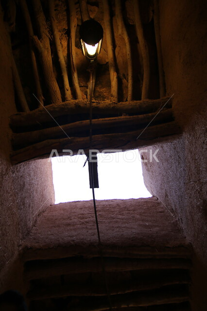 سقف خشبي مع فانوس أثري قديم، صورة من الأسفل من داخل إحدى البيوت الاثرية في قرية أشيقر، أماكن و معالم تاريخية لجذب السياح، أصالة وعراقة التراث في المملكة العربية السعودية، أبنية وبيوت طينية قديمة