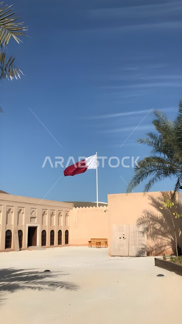 علم دولة قطر يرفرف في السماء الزرقاء, الاحتفال باليوم الوطني القطري, المتحف الوطني الإسلامي للفنون في العاصمة القطرية الدوحة, معالم سياحية مشهورة في وقت النهار، المباني الطينية على الطراز القديم