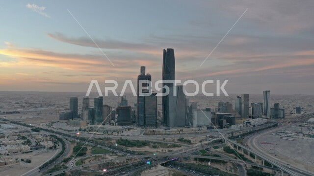 Achieving economic and commercial renaissance, traffic movement on paved roads and streets in the city of Riyadh, urban growth and development in Saudi Arabia, an aerial photo of the King Abdullah Financial Center (KAFD) at sunset, architectural engineering art of the famous buildings and skyscrapers in the Kingdom.