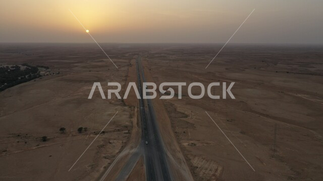صورة جوية لقرية شعيب صلبوخ في مدينة الرياض وقت غروب الشمس، نمو النباتات البرية والأشجار في البراري والصحراء في المملكة العربية السعودية، طريق اسفلتي معبد بين الكثبان الرملية وسط الطبيعة الصحراوية