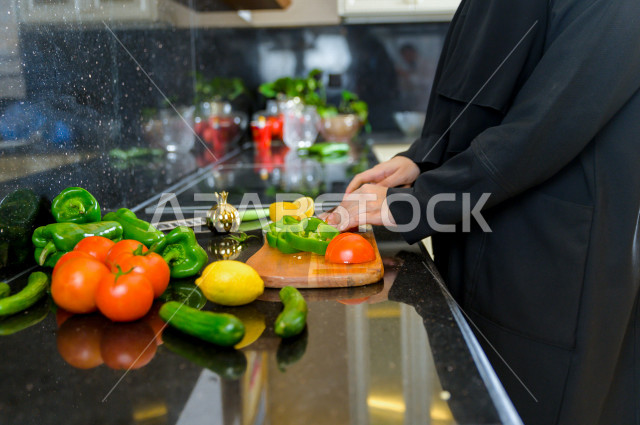 أم سعودية تقوم باعداد وجبه الطعام في المطبخ ، الاستمتاع باداء الاعمال المنزلية ، ايماءات وجه تدل على السعادة و الفرحة