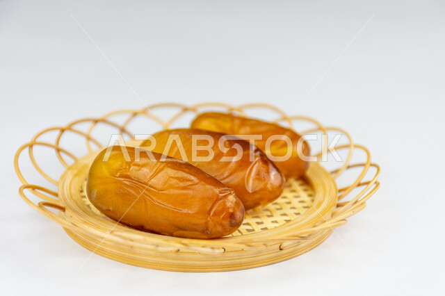 أنواع متختلفة من التمور، ضيافة رمضانية تقليدية، وجبة ذات قيمة غذائية عالية، صورة مقربة لطبق من حبات التمر الصحي شقراء اللون، تمر دقلة نور، خلفية بيضاء