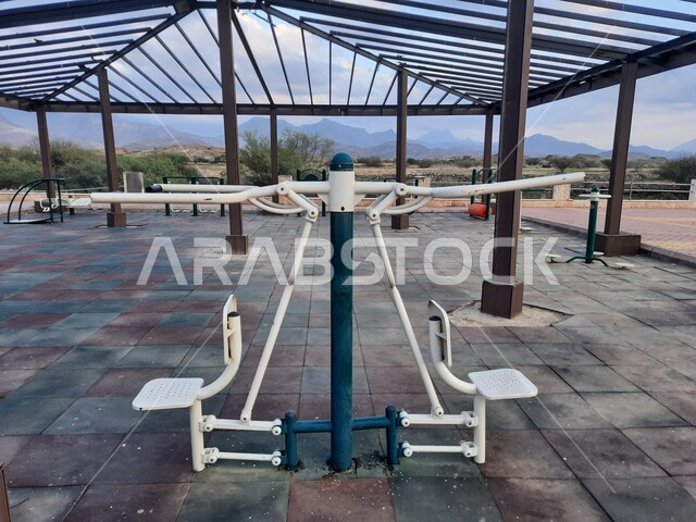 ممارسة التمارين والانشطة الرياضيه في احدى المنتزهات العامه في منطقة الباحة ,مفهوم الحفاظ على الرشاقة والصحة البدنية, صورة مقربة للأجهزة الرياضية الحديثة في مدينة الحجرة في المملكة العربيه السعودية ,أماكن ومناطق سياحية ترفيهيه مشهورة