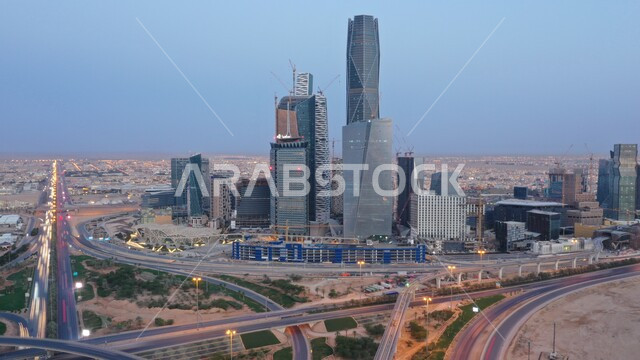 Skyscrapers, financial and economic towers, and architectural facilities, an aerial photo of the city of Riyadh illuminated by lights at night, traffic in the streets, famous tourist landmarks and cities, urban growth and progress in the modern style.