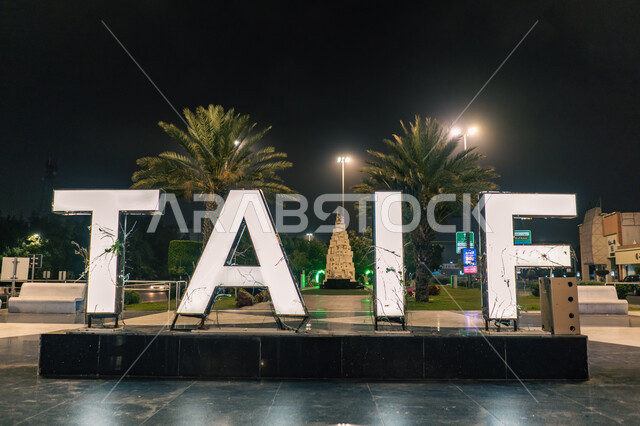 مجسم كلمة الطائف باللغه الانجليزية المضاء ليلا في إحدى منتزهات السعودية, أبرز المعالم السياحة المشهورة, الحدائق الترفيهية العامة في مدينة الطائف ,الاستمتاع في قضاء أوقات الفراغ مع العائلة بالعطلة الصيفية, الاهتمام في زراعة اشجار النخيل و النباتات الخضراء