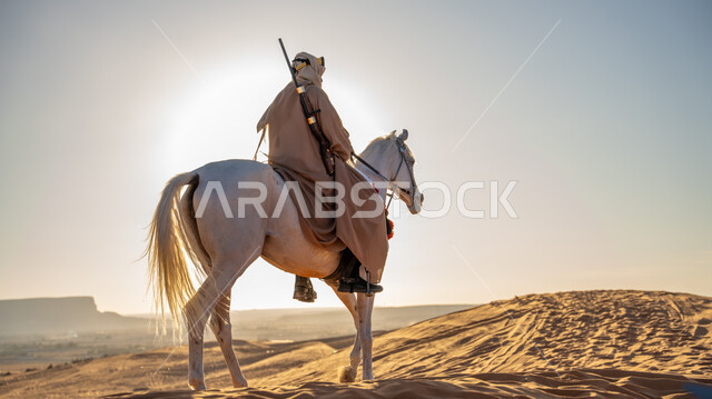 توارث حب وشغف تربية الخيول بين أبناء الوطن، التجول على ظهر الفرس الأبيض الأصيل في إحدى صحاري المملكة, يوم بدينا 1727 م, ذكرى تأسيس الدولة السعودية الأولى 22 فبراير, فارس عربي خليجي سعودي يرتدي البشت والغترة مع العقال الذهبي يمارس هواية ركوب الخيل في النهار