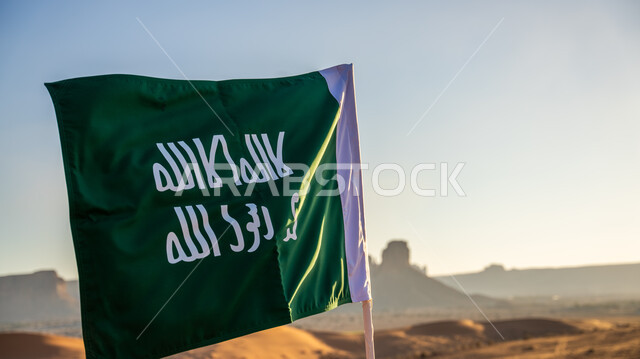 ذكرى تأسيس الدولة السعودية الأولى في 22 فبراير، الفخر والاعتزاز والتباهي بإنجازات وأصالة الوطن، شعار الهوية الوطنية وراية الإسلام والتوحيد، يوم بدينا 1727 م، صورة مقربة لعلم التأسيس مغروس في الرمال الذهبية في النهار