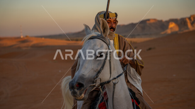 ممارسة هواية ركوب الخيل في إحدى صحاري المملكة، ذكرى يوم بدينا 1727 م، تأسيس الدولة السعودية الأولى 22 فبراير, فارس عربي خليجي سعودي يرتدي البشت والغترة مع العقال يتجول على ظهر فرسه الأبيض الأصيل فوق الرمال الذهبية، توارث حب وشغف تربية الخيول بين أبناء الوطن