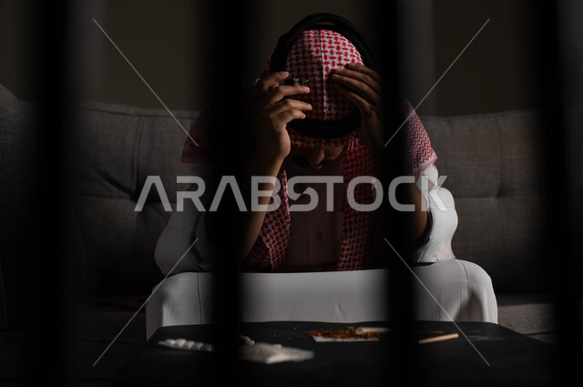 معاقبة النفس وتأنيب الضمير، المعاناة من الاضطرابات النفسية والمشاكل الصحية، بورتريه لرجل عربي خليجي سعودي يرتدي الشماغ والثوب التقليدي يجلس على الاريكة بتعابير التعب والندم، الآثار السلبية للادمان والتعاطي، القيام بعادات سلوكية ضارة وتعاطي المواد السامة