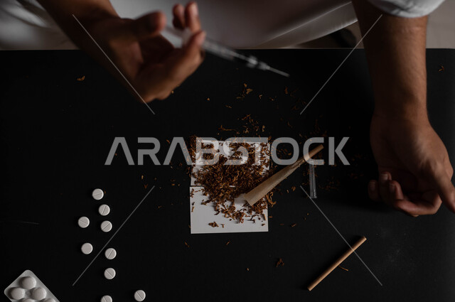 المعاناة من الاضطرابات النفسية والمشاكل الصحية، تعاطي المخدرات عن طريق الحقن في الأوردة، الآثار السلبية للادمان، القيام بعادات سلوكية ضارة وتعاطي المواد السامة، صورة مقربة لرجل عربي خليجي سعودي يرتدي الشماغ والثوب التقليدي يقوم بأخذ جرعة مخدرة