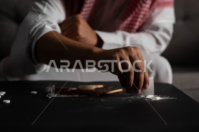 اتباع عادات سلوكية ضارة وتعاطي المواد السامة، المعاناة من الاضطرابات النفسية والمشاكل الصحية، صورة مقربة لرجل عربي خليجي سعودي يقوم باستخدام المواد المخدرة، الآثار السلبية للادمان والتعاطي