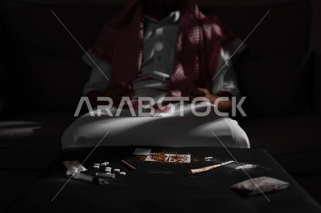 معاقبة النفس وتأنيب الضمير، المعاناة من الاضطرابات النفسية والمشاكل الصحية، بورتريه لرجل عربي خليجي سعودي يرتدي الشماغ والثوب التقليدي يجلس على الاريكة بتعابير التعب والندم، الآثار السلبية للادمان والتعاطي، القيام بعادات سلوكية ضارة وتعاطي المواد السامة