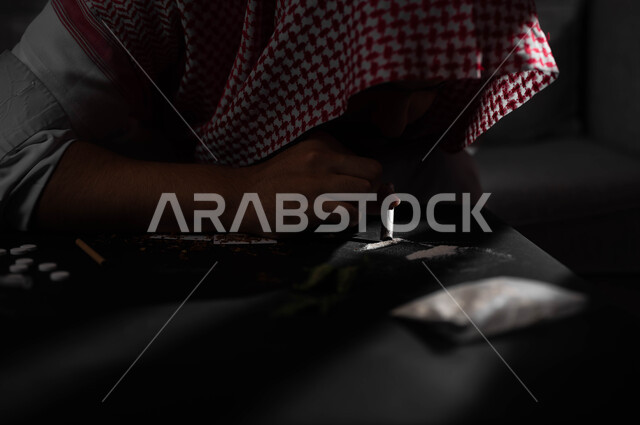 استنشاق وتعاطي المواد السامة، القيام بعادات سلوكية ضارة، المعاناة من الاضطرابات النفسية والمشاكل الصحية، الآثار السلبية للادمان، صورة مقربة لرجل عربي خليجي سعودي يرتدي الشماغ والثوب التقليدي يقوم بشم المخدرات