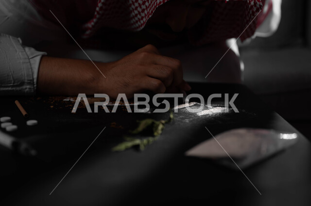 اتباع عادات سلوكية ضارة، استنشاق وتعاطي المواد السامة، المعاناة من الاضطرابات النفسية والمشاكل الصحية، الآثار السلبية للادمان، صورة مقربة لرجل عربي خليجي سعودي يرتدي الشماغ والثوب التقليدي يقوم بشم المخدرات