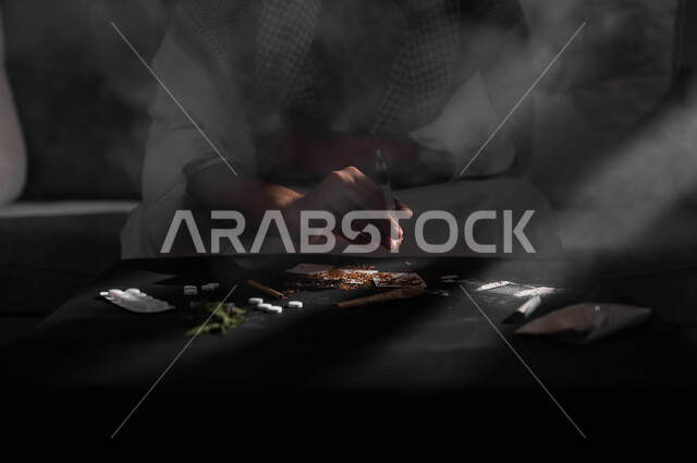 Injecting drugs into veins, the negative effects of addiction, engaging in harmful behavioral habits and taking toxic substances, suffering from psychological disorders and health problems, a close-up silhouette of a Saudi Gulf Arab man wearing a shemagh and traditional dress, sitting on the sofa taking an anesthetic needle.