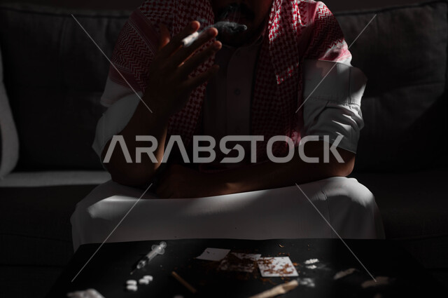 اتباع عادات سلوكية خاطئة، تعاطي مواد ضارة وسامة، الادمان على تدخين التبغ والسجائر، الإصابه بأمراض الجهاز التنفسي، صورة مقربة لشاب عربي سعودي خليجي يرتدي الشماغ والثوب التقليدي يمسك بيده السيجارة