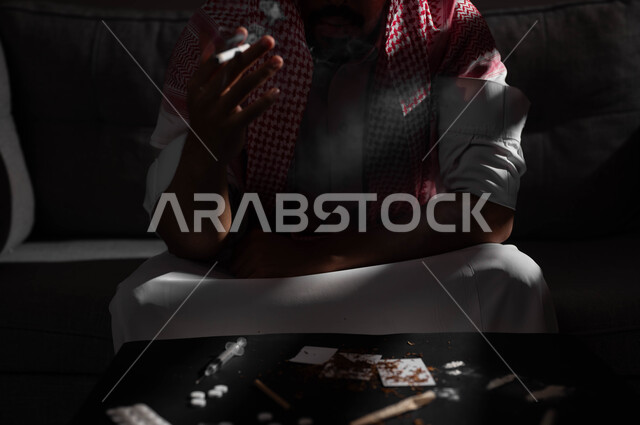 تعاطي مواد ضارة وسامة، الادمان على تدخين التبغ والسجائر، اتباع عادات سلوكية خاطئة، الإصابه بأمراض الجهاز التنفسي، صورة مقربة لشاب عربي سعودي خليجي يرتدي الشماغ والثوب التقليدي يمسك بيده السيجارة